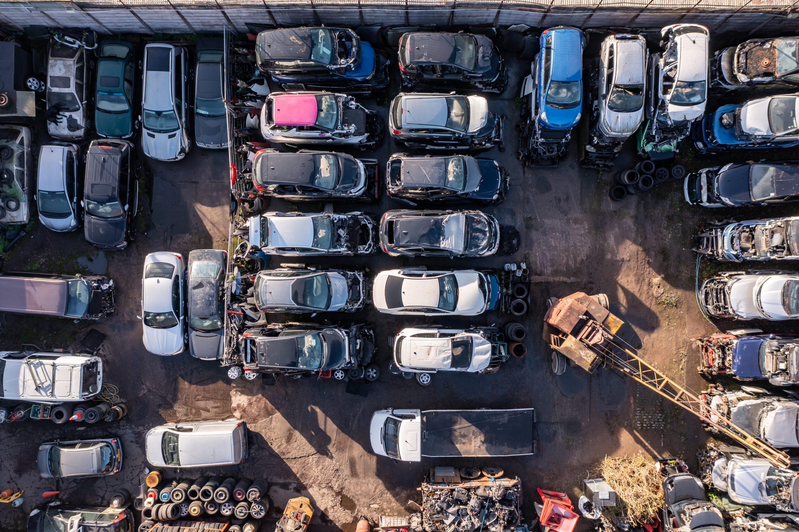 BIRMINGHAM, UK - OCTOBER 17, 2022. Aerial view directly above rows of scrap metal cars involved in traffic accidents in a car insurance concept background with copy space