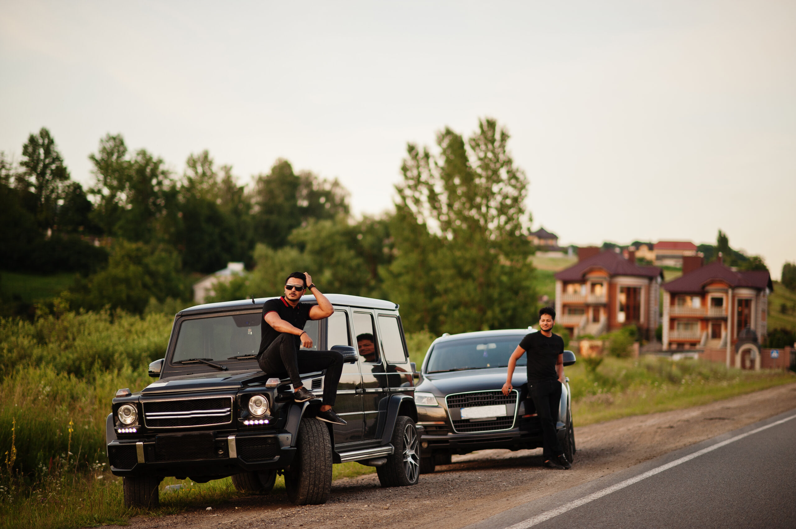 Two asian brothers man wear on all black posed near suv cars.