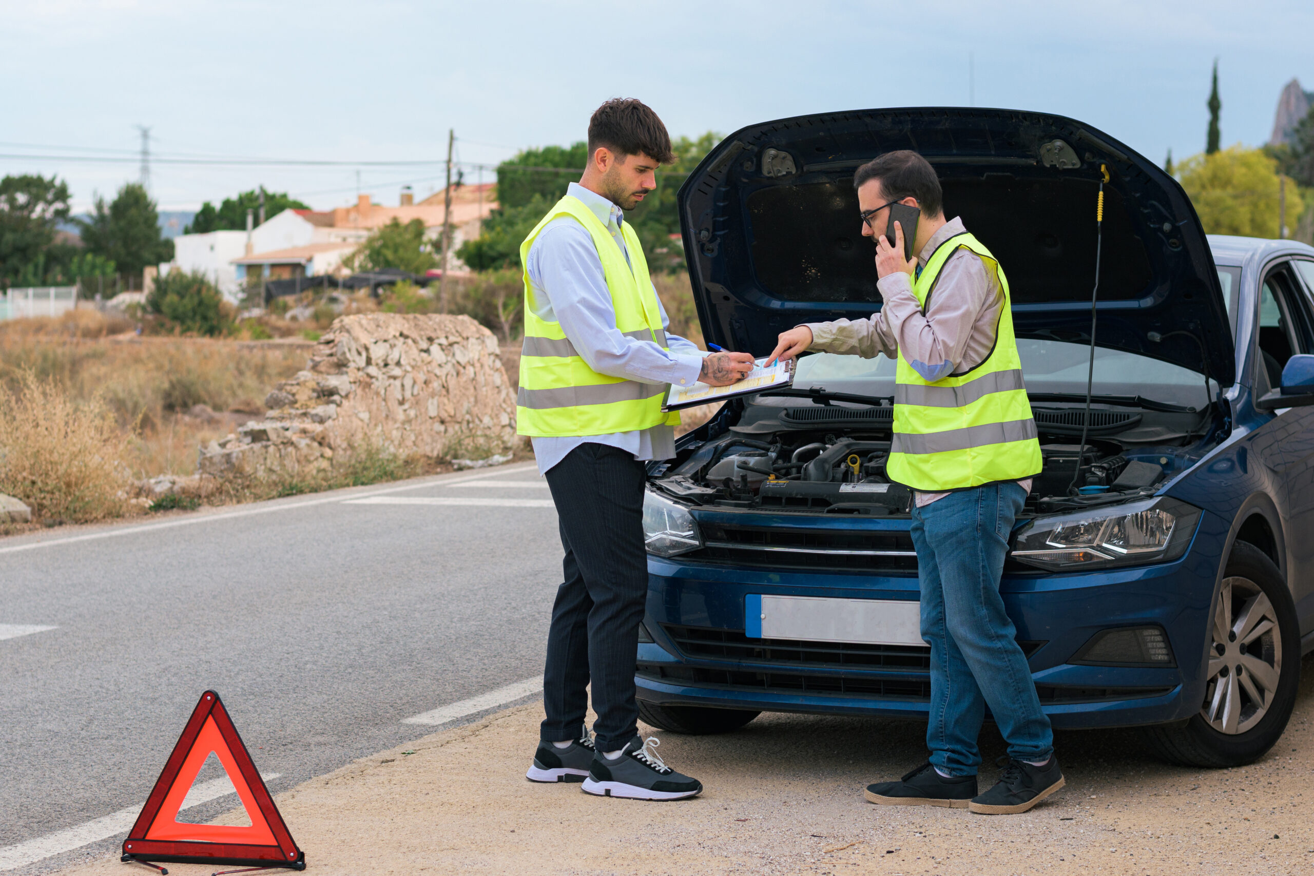 Two men look at a report crash after a collision between cars