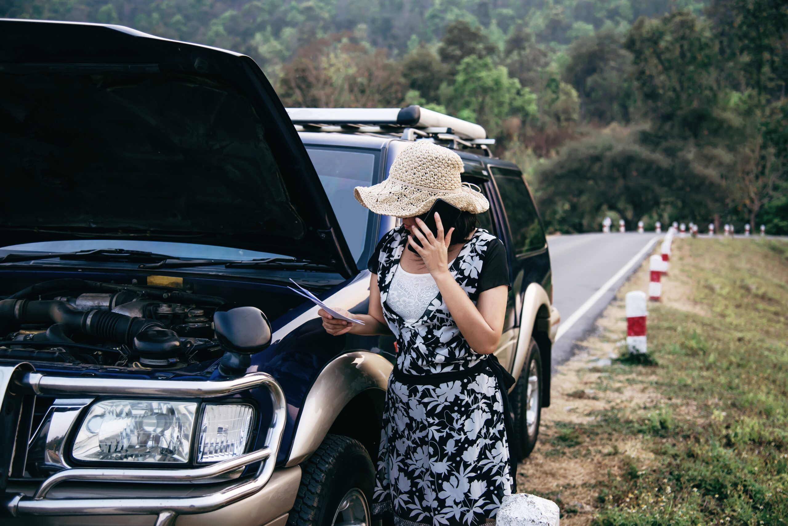 Asian woman calling repairman or insurance staff to fix a car engine problem on a local road - people with car problem transportation concept