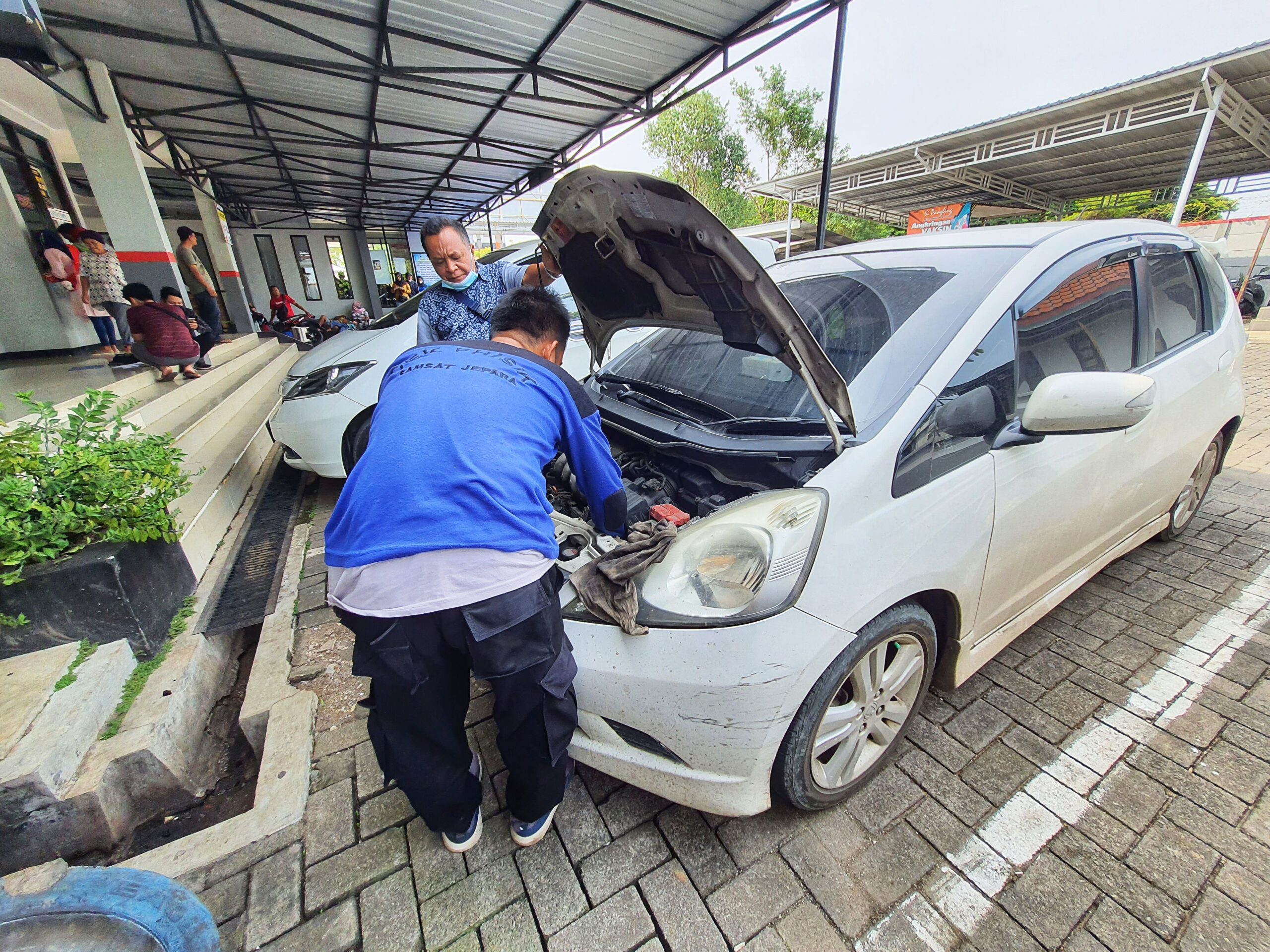 Central Java, Indonesia in October 2022. An officer is carrying out a physical check of a vehicle that will extend or replace its license plate number. This place of service is called SAMSAT or One-Stop Administration Services Office.
