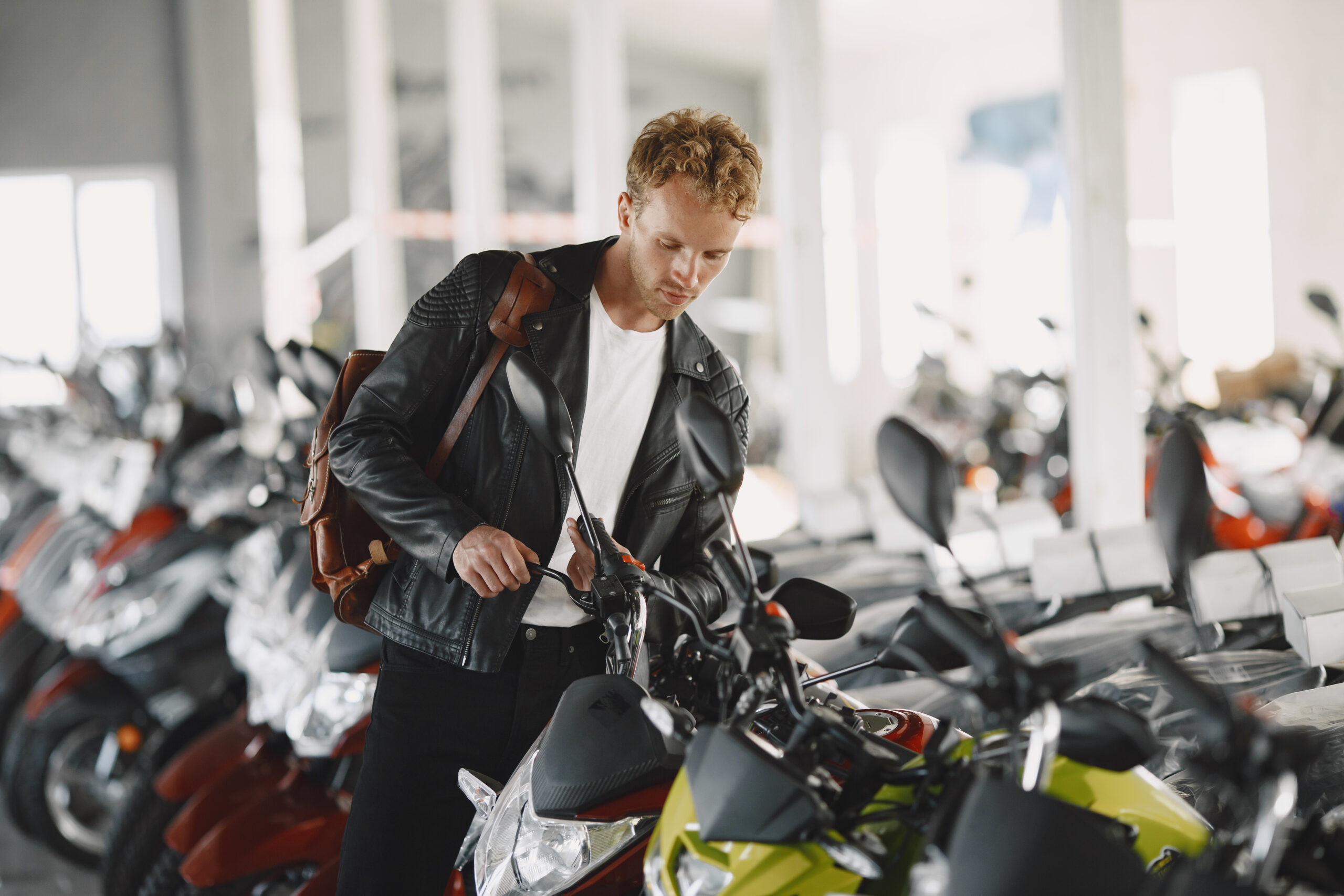 Man choosed motorcycles in moto shop. Guy in a black jacket.