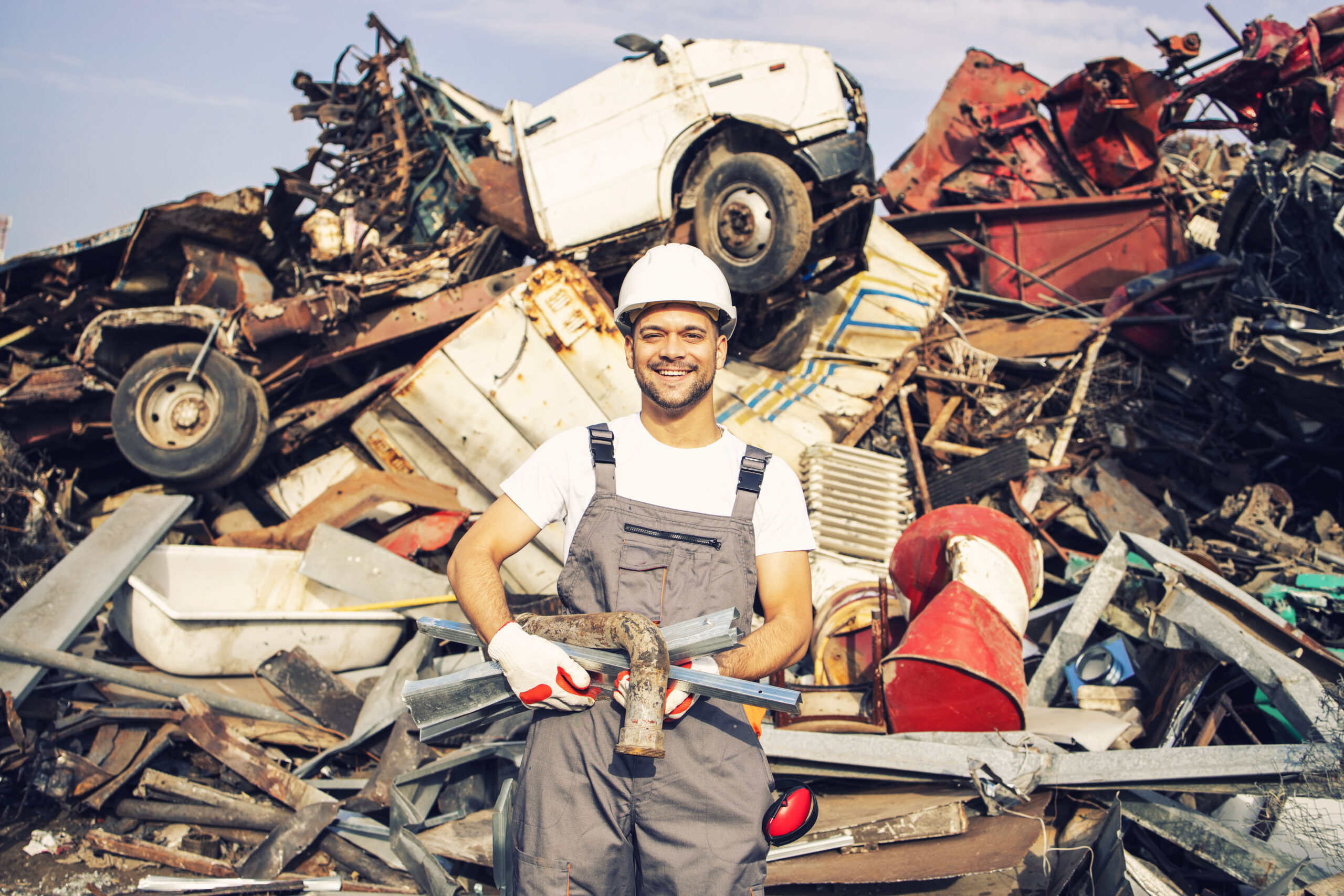 Portrait of junk yard worker holding metal parts.