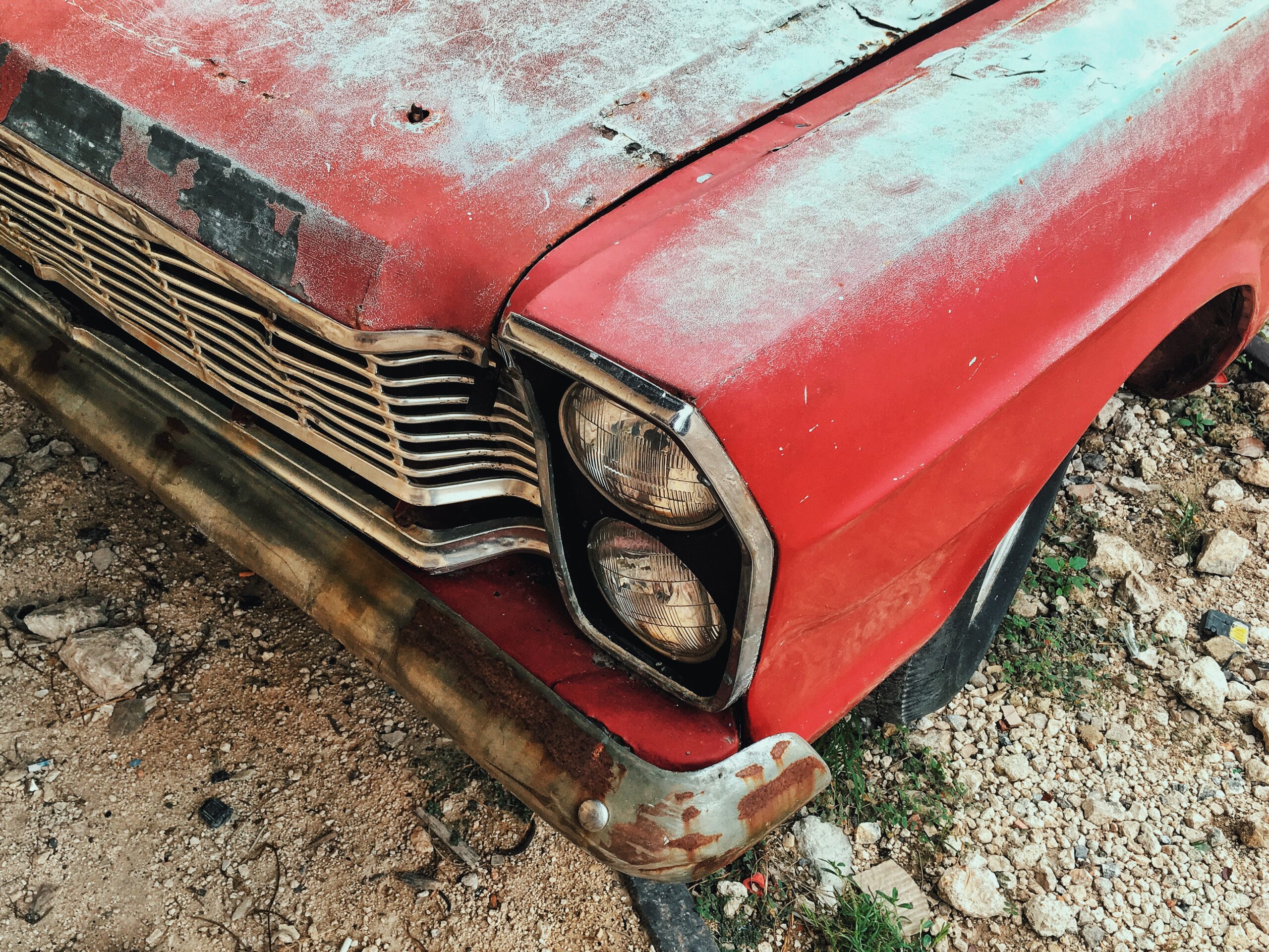 A front of an old vintage dirty red car