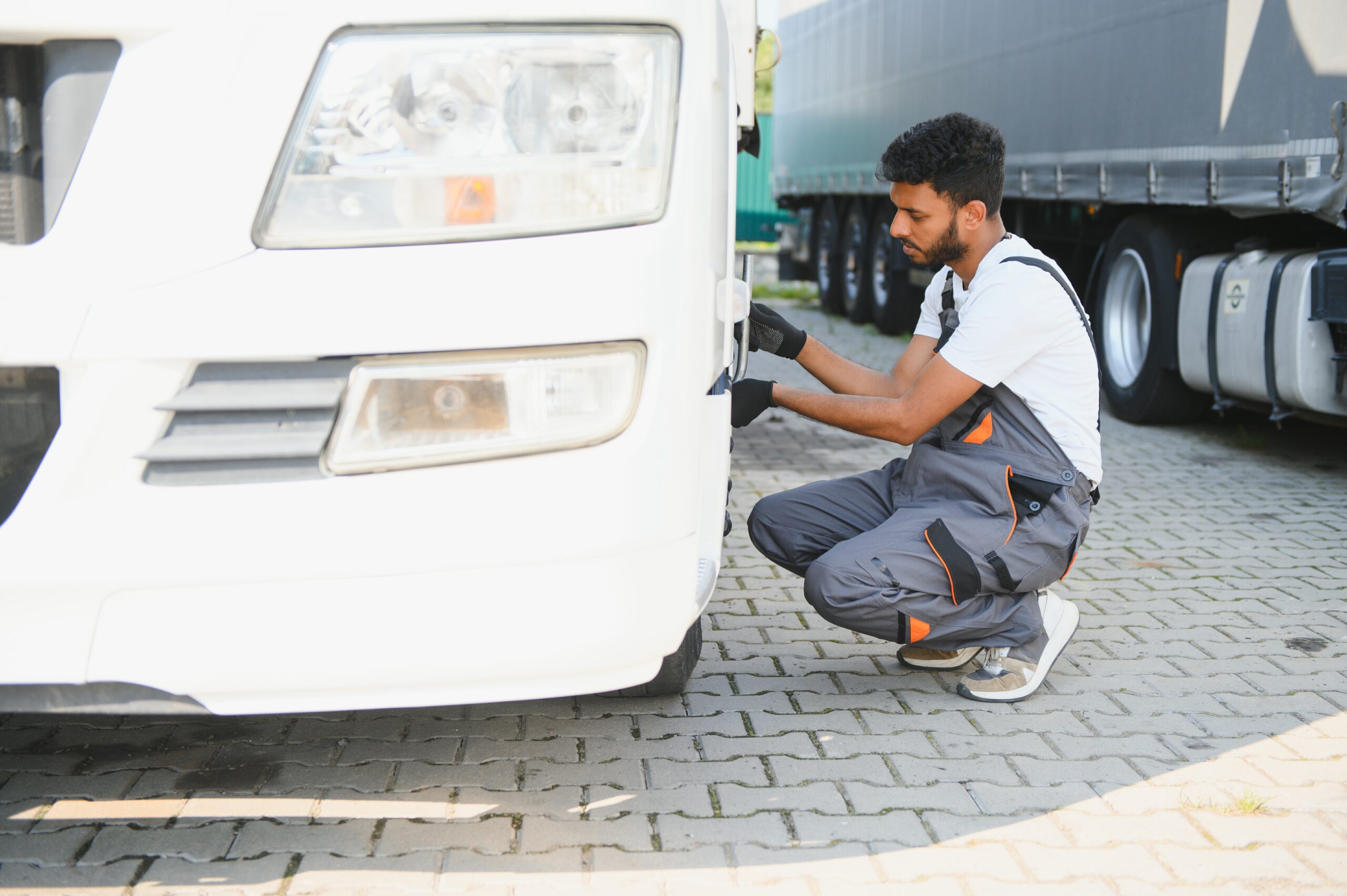 Indian Mechanic unscrews wheel truck pneumatic wrench.